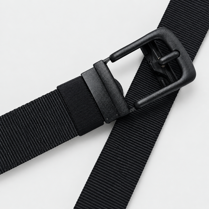 Zwarte BuckleUp Outdoor Belt van nylon, band kruislings gedraaid met de matzwarte automatische gesp prominent in beeld op een effen achtergrond