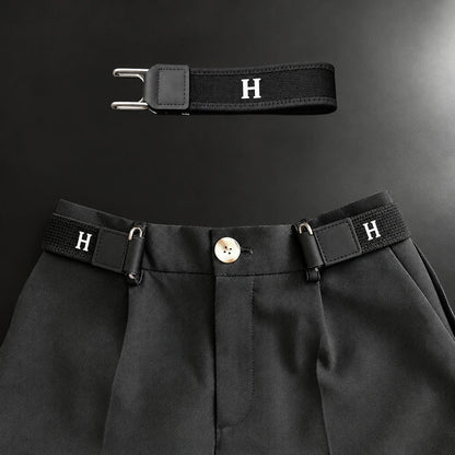 Zwarte gesploze riem aan weerszijden van de knoopsluiting van een nette pantalon, met een los exemplaar erboven